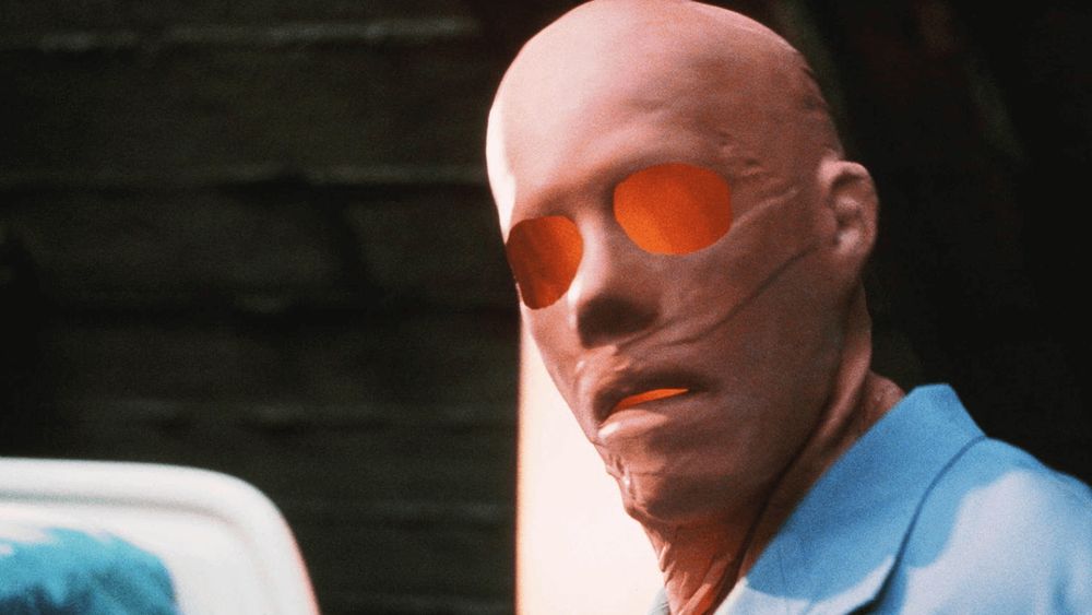An invisible Sebastian Cane (Kevin Bacon) in a mask and clothes but without his eyes or mouth looks at the camera in in Hollow Man (2000)