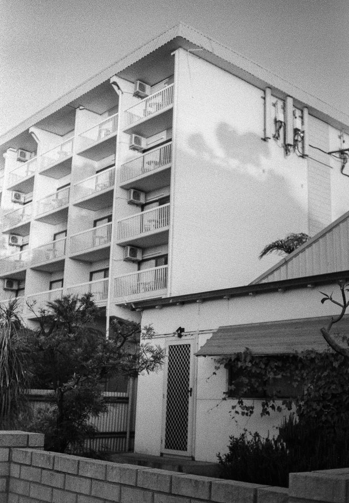 A view of the hotel from the front corner showing a similarly aged single level plain asbestos/gyprock panel house. 