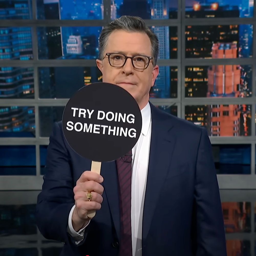 stephen colbert holding up sign saying 'try doing something'. mocking the goofball signs democrats held up at the bonkers stupid trump congressional address. 