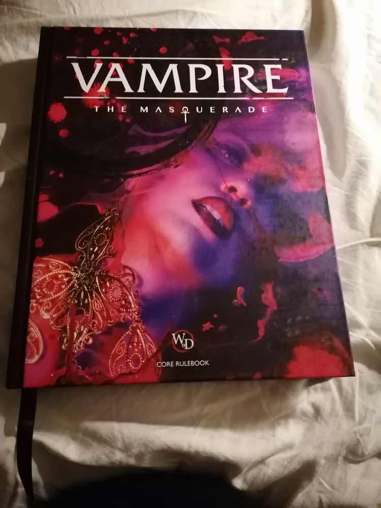 Book cover of Vampire the masquerade core rulebook with the face of a woman whose red lips are parted.