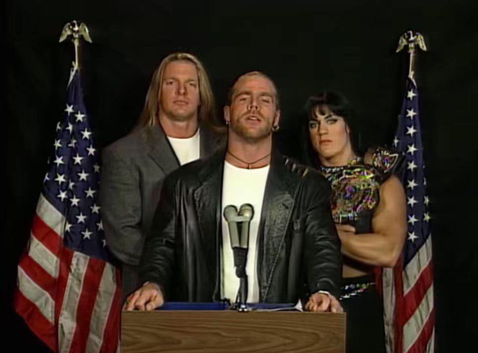Triple H, Shawn Michaels, and Chyna at the infamous "DX address" segment, standing behind a presidential podium with American flags.