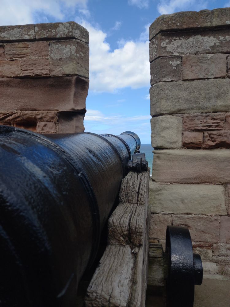 Looking along the barrel of a 24-pounder cannon. The cannon is on a castle wall, aimed out into the North Sea.