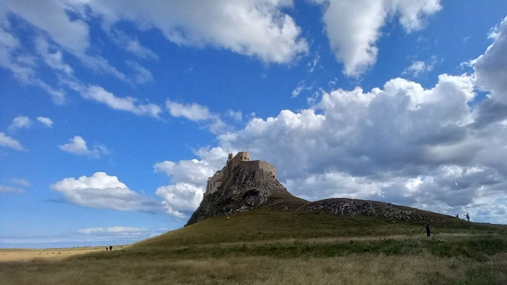Lindisfarne Castle, against a blue sky with white clouds.