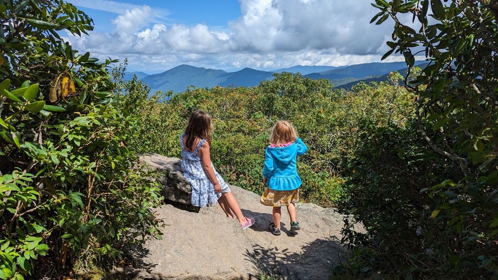 Two children stare out into the distance at a mountain vista.