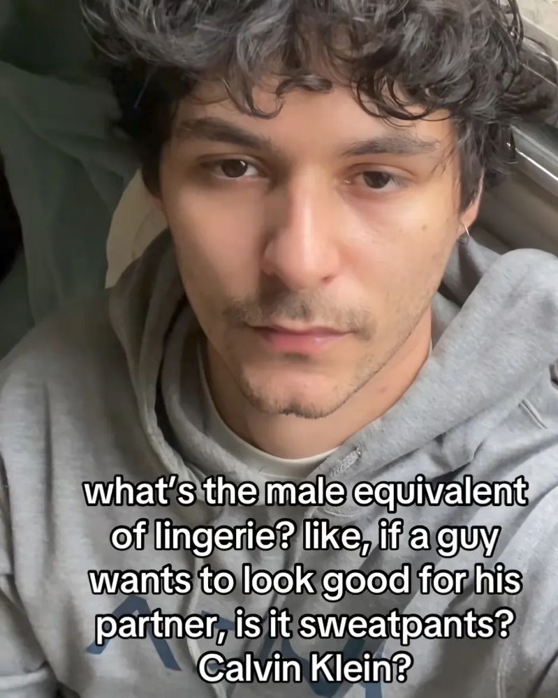 a screenshot of a tiktok. a man in a grey hoodie is looking at the camera. its captioned "what's the male equivalent of lingerie? like, if a guy wants to look good for his partner, is it sweatpants? Calvin klein?"