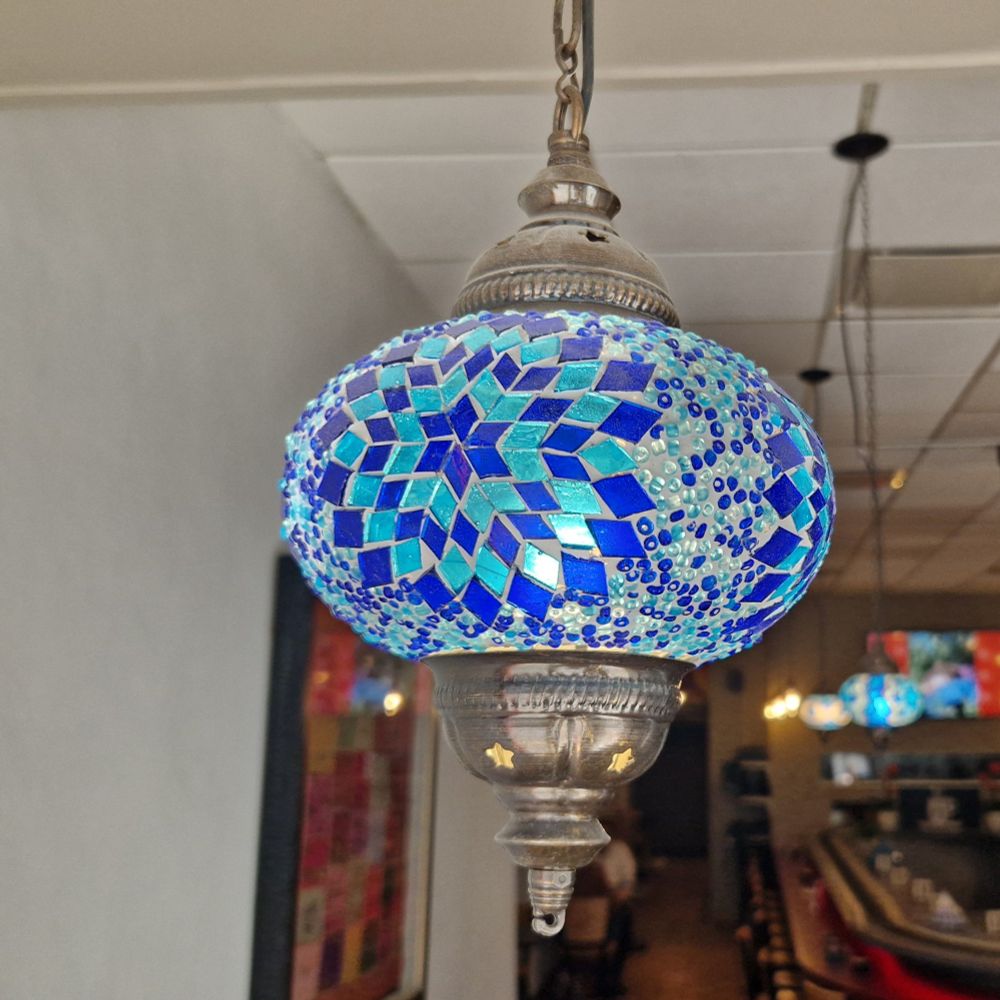 A decorative glass light fitting with dark and light rhombus shapes arranged in a six pointed star pattern