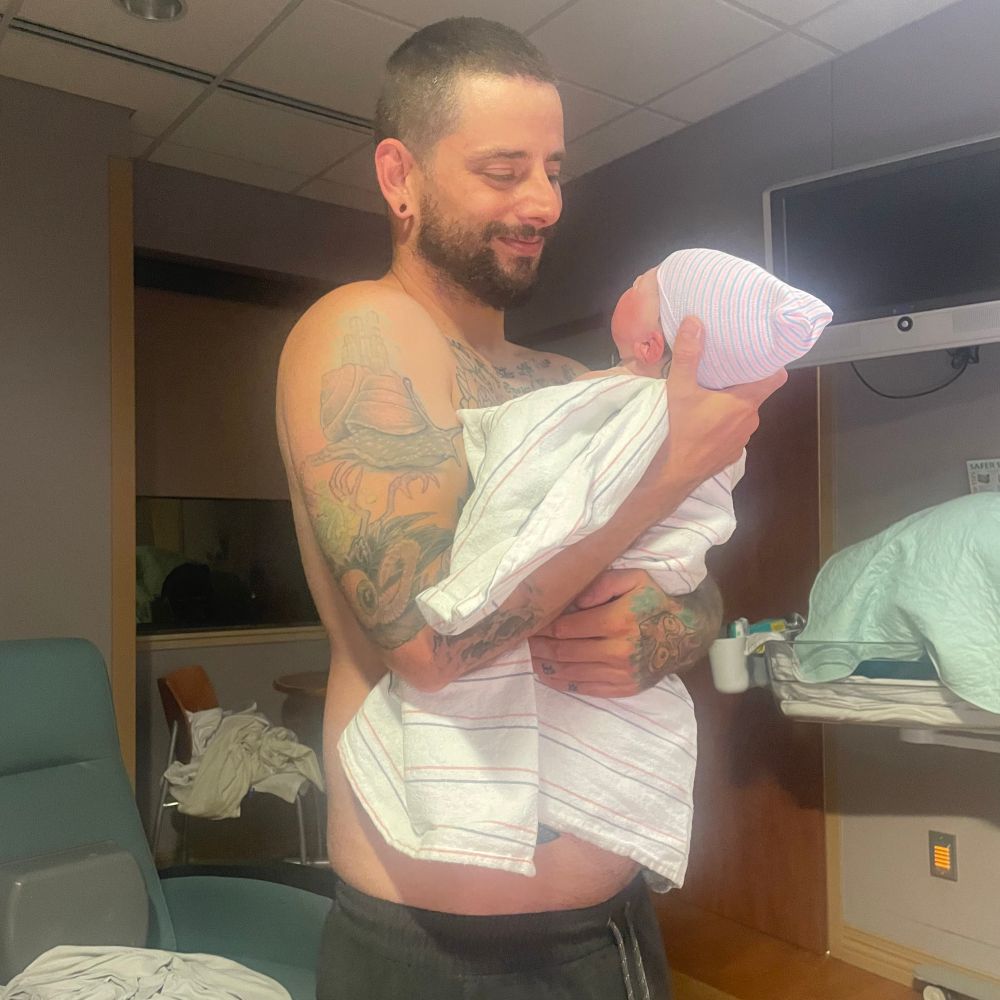 Dad holding baby in a hospital room 