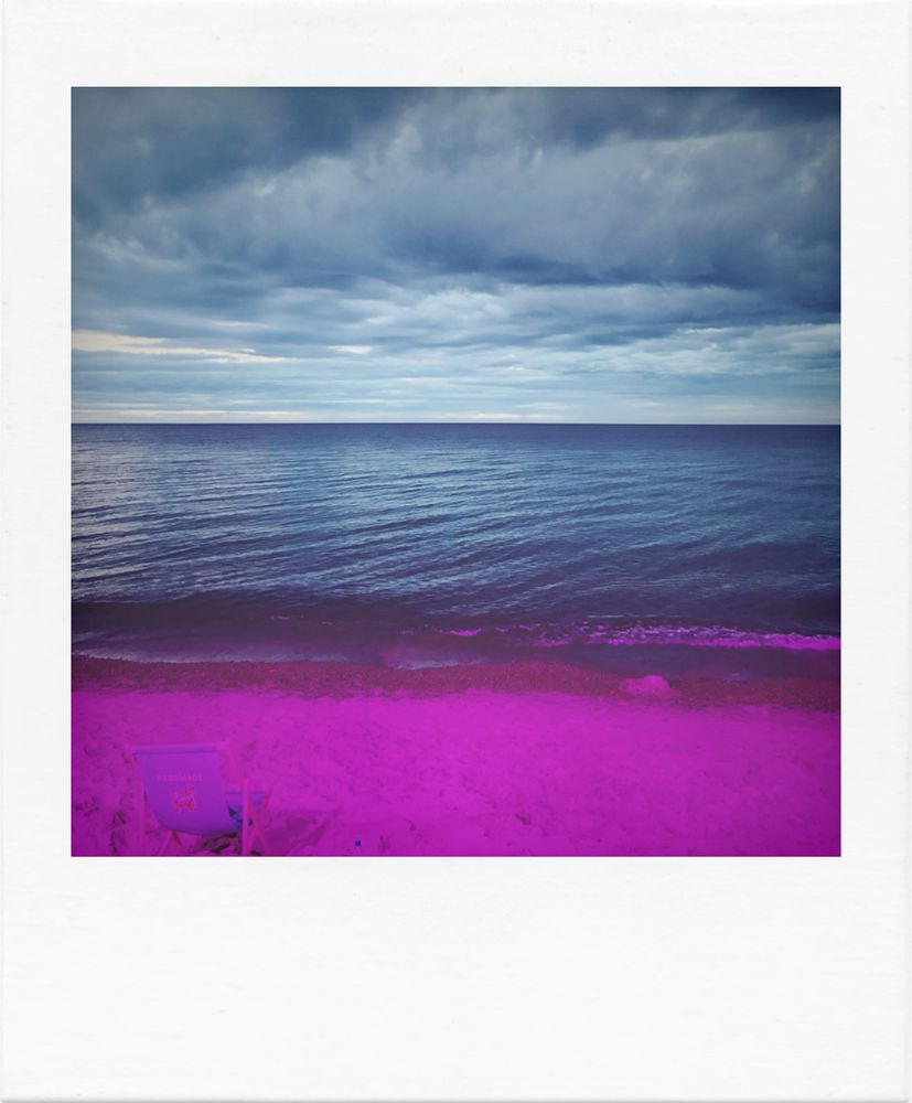 Blick auf die Ostsee. Davor ein pink-farben beleuchteter Strand. 