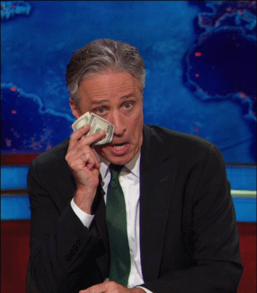 a man in a suit and tie holds a wad of money in his hand