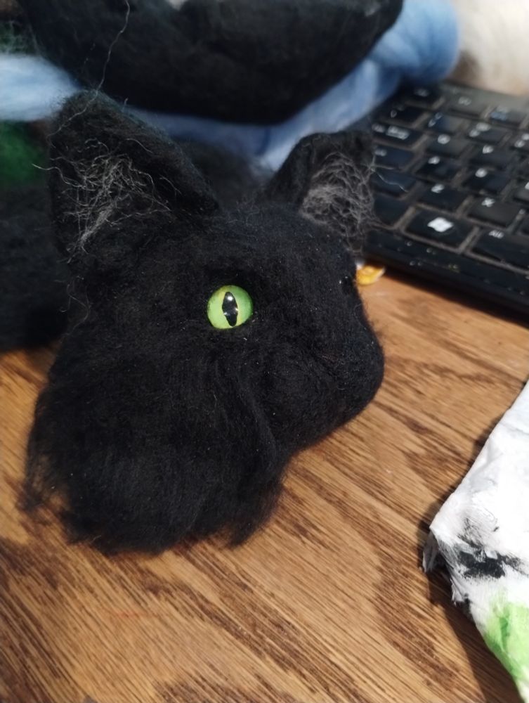Painted glass eye in a partially complete needlefelted cat head