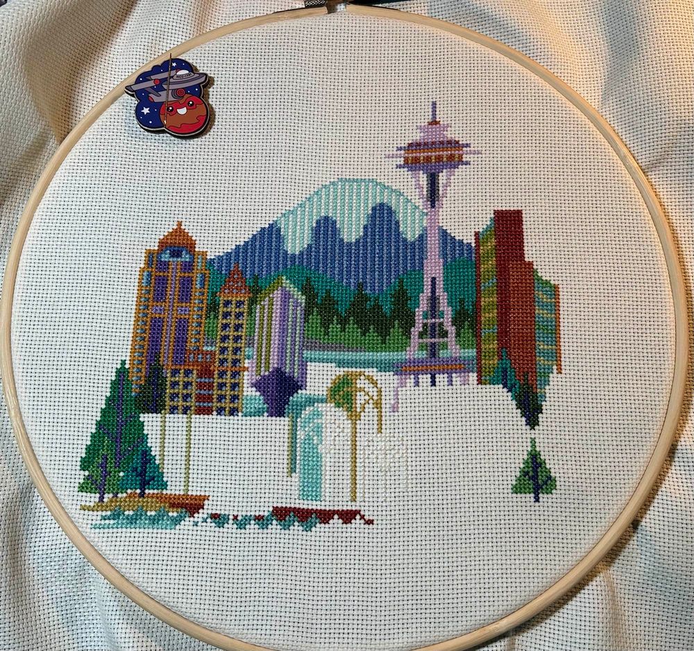 Incomplete cross stitch of a whimsical Seattle skyline