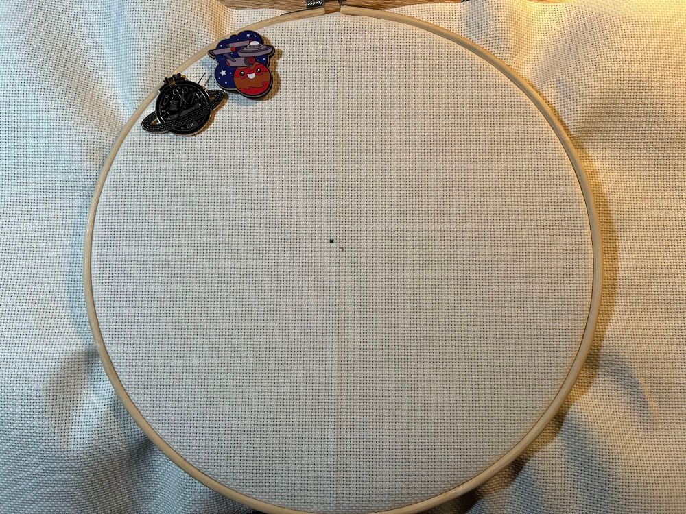 An embroidery hoop with fabric and one stitch
