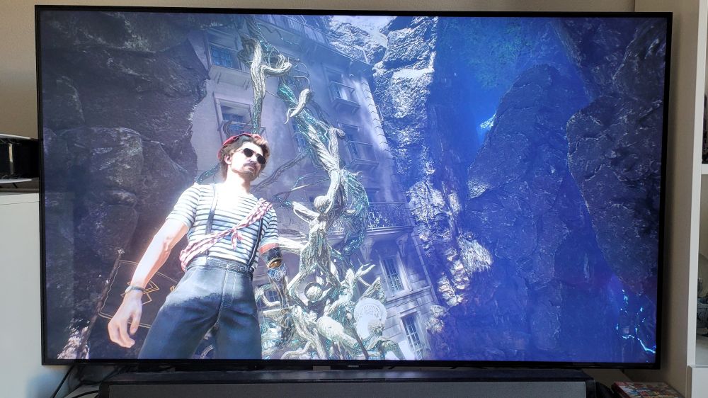 Une photo tirée de Clair Obscur Expedition 33, où l'on voit Gustave, le héros, vêtu d'un t-shirt à rayures et d'un pantalon à bretelles, avec des lunettes de soleil et un béret rouge dans le plus pur cliché du mime parisien. Un torchon à carreaux rouge et blanc est passé en bandoulière.