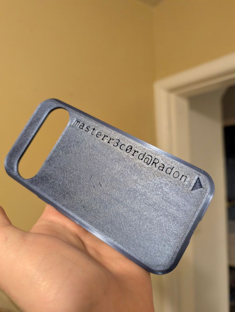 Picture of a 3D printed phone case for the Pixel 9, with the text "masterr3c0rd@Radon" engraved into it.
